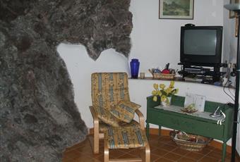 sala con parete di roccia naturale con angolo TV e pranzo Sicilia ME Lipari