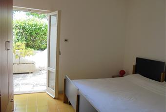 La camera è luminosa, si apre sul patio verde, il pavimento è piastrellata Puglia LE Otranto